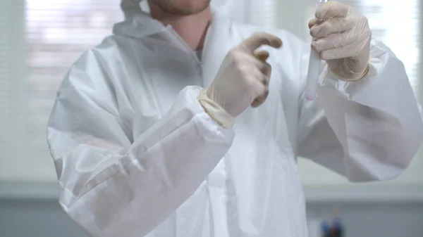 Νεαρός επιστήμονας σε προστατευτικό σωλήνα εργασίας ανακινήσει με χημική ουσία και να εξετάσουμε στο εργαστήριο — Φωτογραφία Αρχείου
