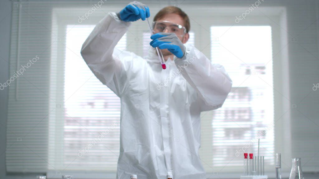 Scientist in protective workwear and gloves work with chemicals in the laboratory