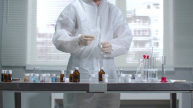 Koruyucu iş kıyafetleri ve eldivenler bilim adamı laboratuara bir şey yerleştirdi.