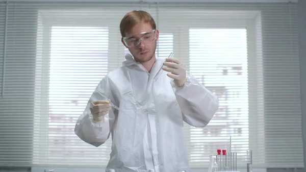 Científico joven en ropa de trabajo protectora y guantes trabaja con productos químicos en el laboratorio —  Fotos de Stock