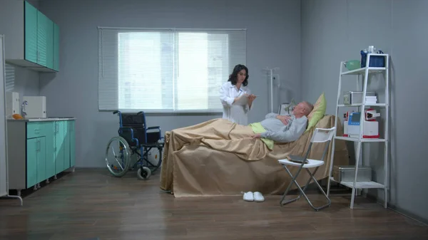 Doutor com conversa com paciente que está deitado na cama no hospital — Fotografia de Stock