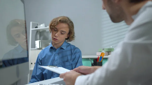 Dokter praat met jongen in ziekenhuiskabinet — Stockfoto