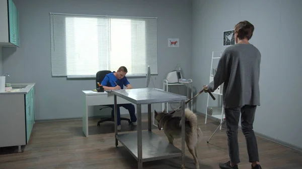 Hombre con perro pasea en el gabinete del médico veterinario — Foto de Stock