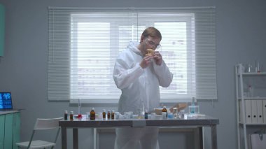 Koruyucu iş kıyafetli adam laboratuardaki şeylerin kokusunu alıyor.