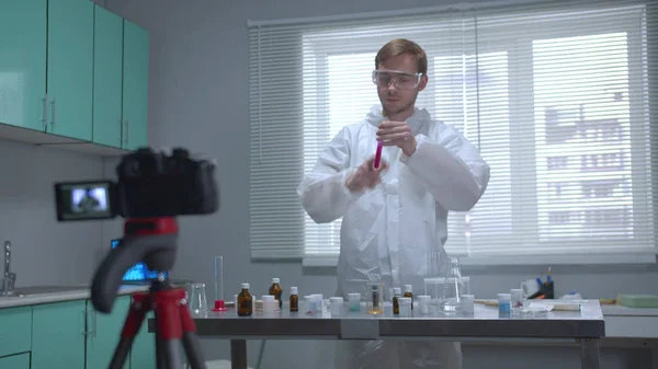 Человек в защитной трубке с химикатами на камере в лаборатории — стоковое фото