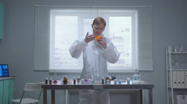 Koruyucu giysili adam masadaki şeylerin kokusunu alıyor. 