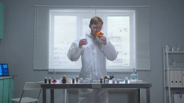 En cámara lenta, el hombre en ropa de trabajo protectora huele cosas en el laboratorio —  Fotos de Stock