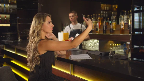 Barman limpa um copo, mulher faz selfie — Fotografia de Stock
