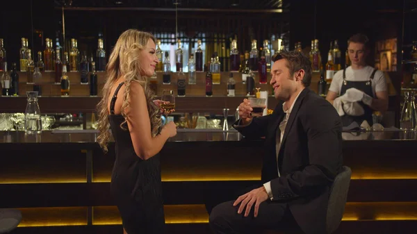 Woman starts to talk to handsome man at the bar