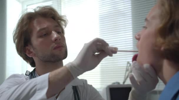 Doctor check jongen keel met stok in de kast van het ziekenhuis, zijaanzicht — Stockvideo