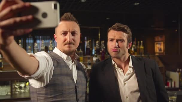 Dva muži stojí u baru a dělají selfie na telefonu — Stock video
