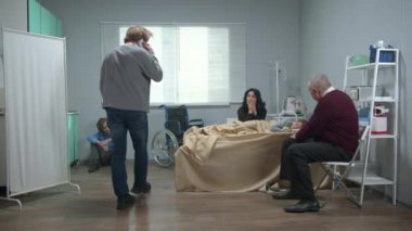People visit girl in the hospital, they sit and wait, man talk on phone nervously