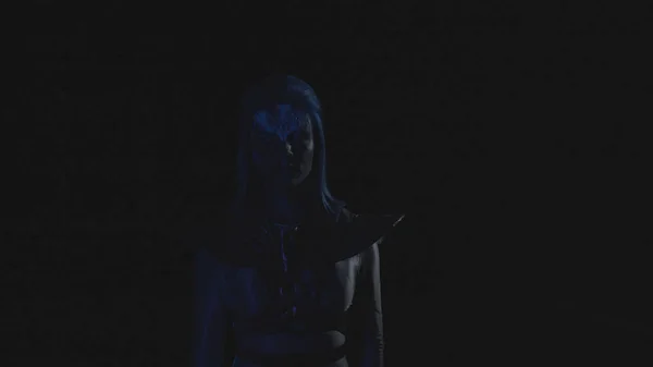 Женщина с сияющим голубым лицом смотрит в камеру, когда свет мигает — стоковое фото