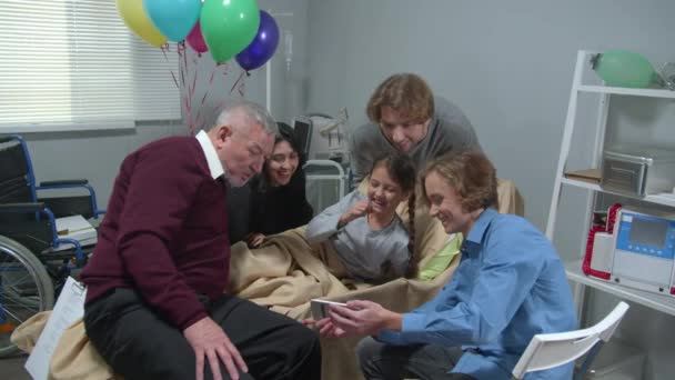 Familiares visitan chica en el hospital, chico mostrar fotos a todo el mundo — Vídeos de Stock