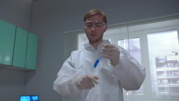 Scienziato in tubo di agitazione protettivo da lavoro con prodotto chimico e spostarlo in laboratorio — Video Stock