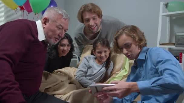 As pessoas visitam menina no hospital, foto do show do menino e todos riem — Vídeo de Stock