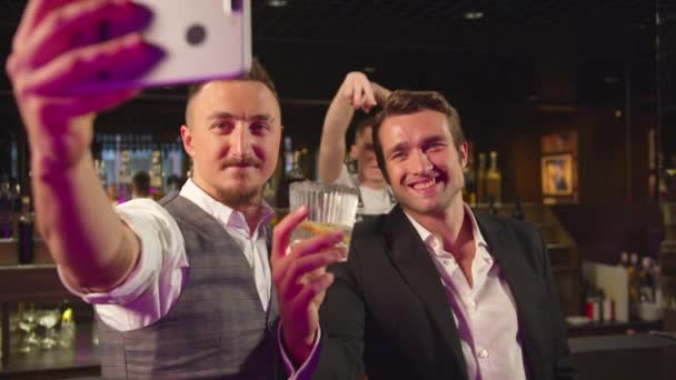 Deux hommes se tiennent au bar et font un selfie avec de l'alcool et un barman — Video