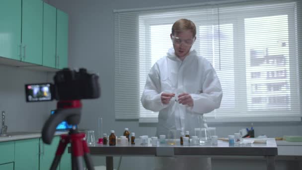 Homem em vestuário de trabalho de proteção despeje líquido em tubo na câmera no laboratório — Vídeo de Stock