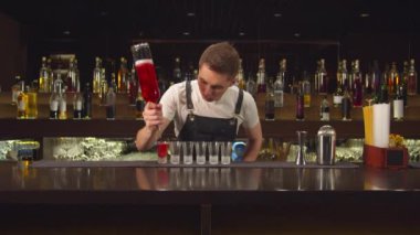 Barmen kadehlere birer birer alkol doldurur.