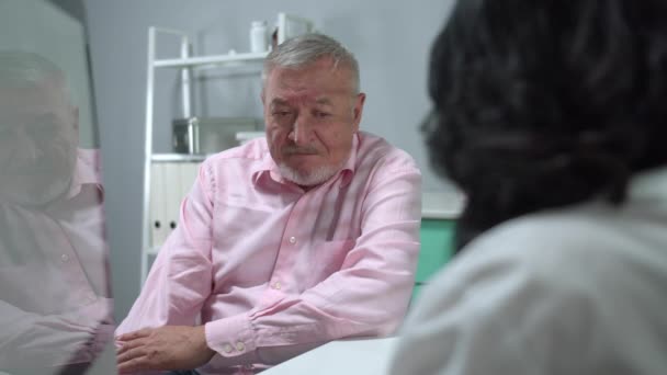 Old man sit in cabinet of hospital and listen to the doctor — 비디오