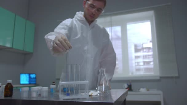 Cientista em vestuário de trabalho de proteção despeje líquido em tubos no laboratório — Vídeo de Stock