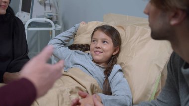 Relatives come to visit and to talk to girl who lie on the bed in the hospital