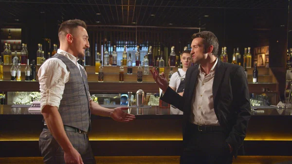 Двое мужчин стоят в баре и агрессивно разговаривают друг с другом. — стоковое фото