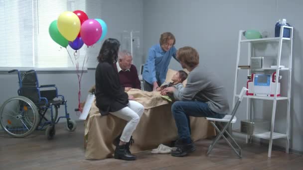 Verwandte besuchen Mädchen, das im Krankenhaus auf dem Bett liegt — Stockvideo