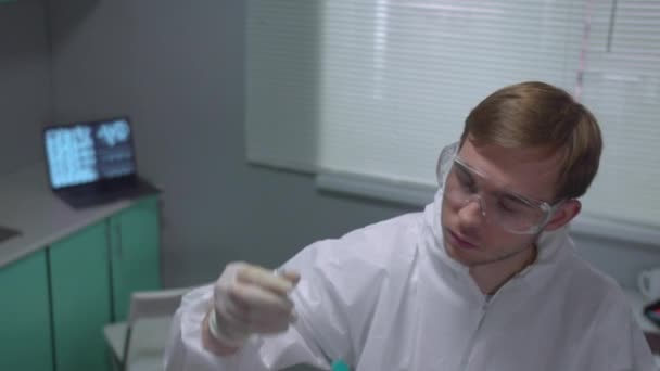 Slow motion, chemist in protective workwear shake tube with blue liquid in the laboratory — Stock Video