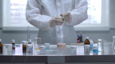 Koruyucu iş kıyafetli adam laboratuarda yanan şeyin üzerine bir şey döktü.