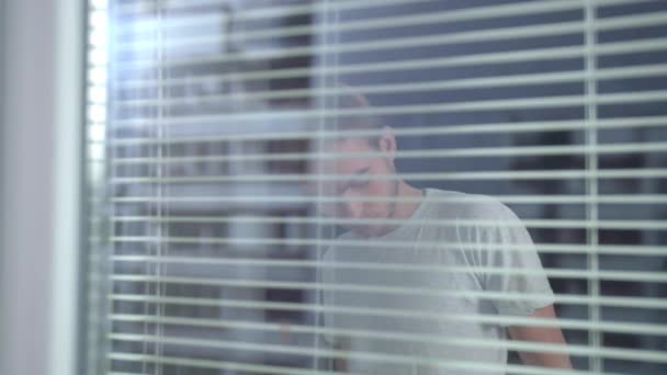 Vista através da janela, homem colocar em branco vestuário de trabalho de proteção — Vídeo de Stock
