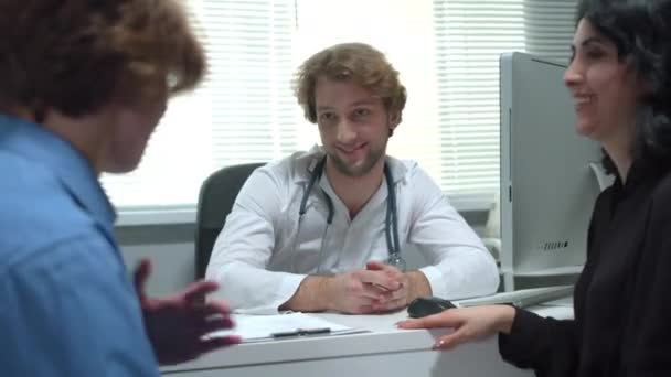 Dokter praat vriendelijk met jongen en moeder in het ziekenhuis — Stockvideo