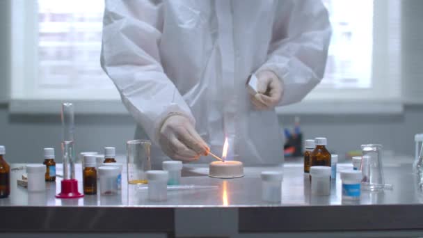 Muž v ochranných pracovních oděvech zapálil látku na stole v laboratoři — Stock video