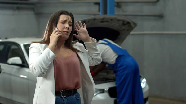 Mécanicien répare une voiture, femme triste parle au téléphone émotionnellement — Photo