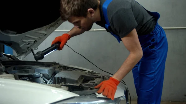 Slow motion, mechanic opens the hood of a car and turns on a flashlight — Stockfoto