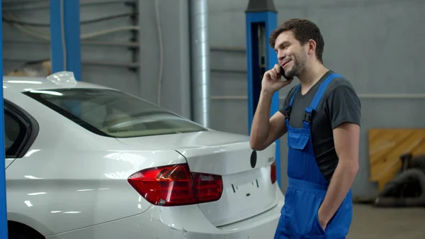 Mechanic talks on phone and discusses car damage — Stockfoto