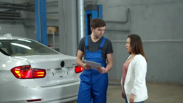 Mechanic discusses the price of a car repair with woman — Stockfoto