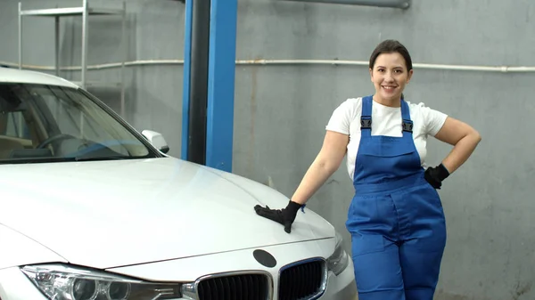 Woman mechanic closes hood of car and smiles in car service — Stockfoto