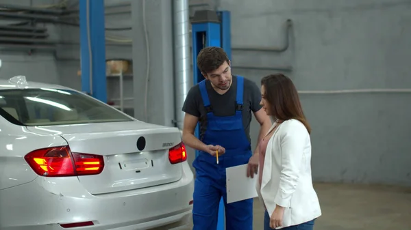 Mechanic shows car damage to a woman — Stockfoto