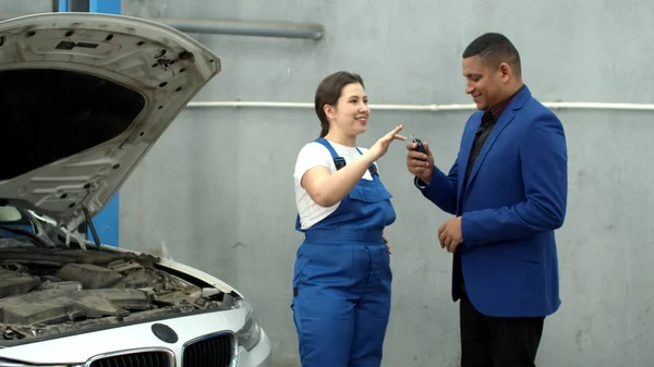 Mekaniker samtalar med ägaren och ger nycklar till bilen — Stockfoto