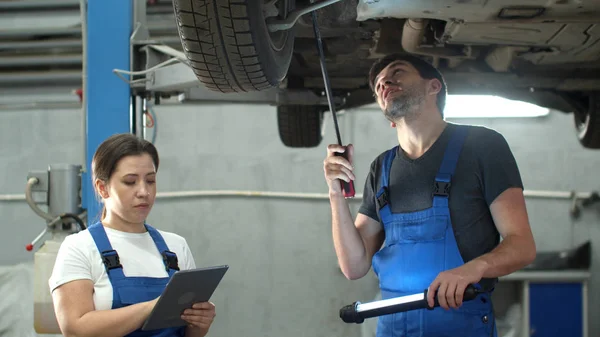 Mechaniker zeigt Autoräder, Frau mit Tablet macht sich Notizen — Stockfoto