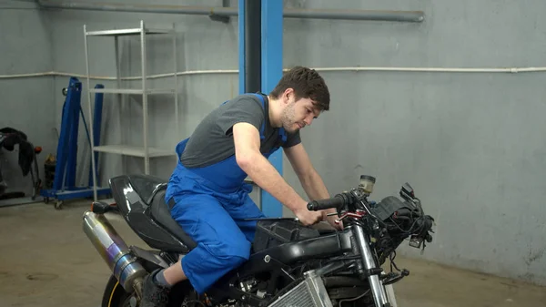 Gerakan lambat, teknisi duduk di sepeda motor dan memperbaikinya — Stok Foto