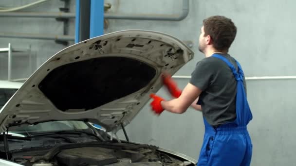 Mechanic closes hood of car and looks at the camera — Stockvideo