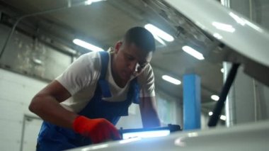 Slow motion, mechanic in uniform repair the motor of car