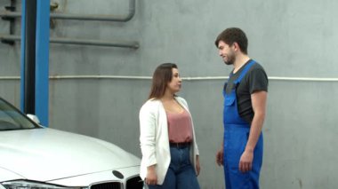 Woman talks to mechanic and gives keys of car