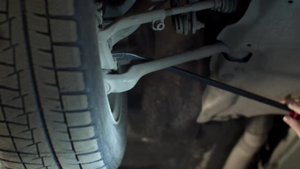 Mechanik s baterkou opravuje auto kolo, zblízka — Stock video