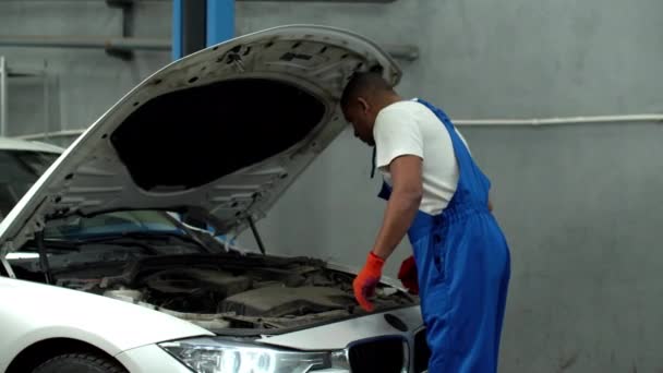 Mecánico abre el capó de un coche y mira el motor — Vídeo de stock