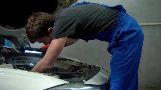 Mecánico con linterna examina el motor del coche — Vídeos de Stock