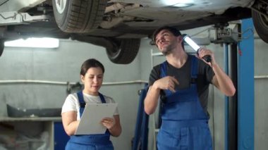 El fenerli tamirci araba çantası gösteriyor, kadın not alıyor.