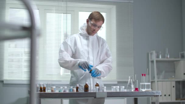 Homme en vêtements de travail et gants de protection travaillent avec des équipements chimiques dans le laboratoire — Video